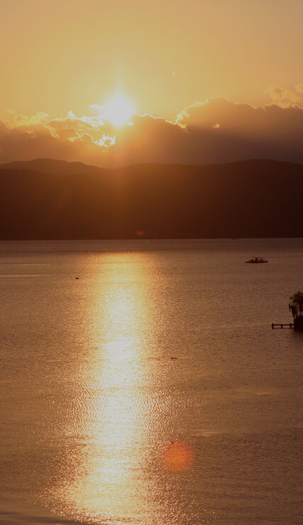 夕日が湖面に反射し、穏やかな時間が流れる湖の風景